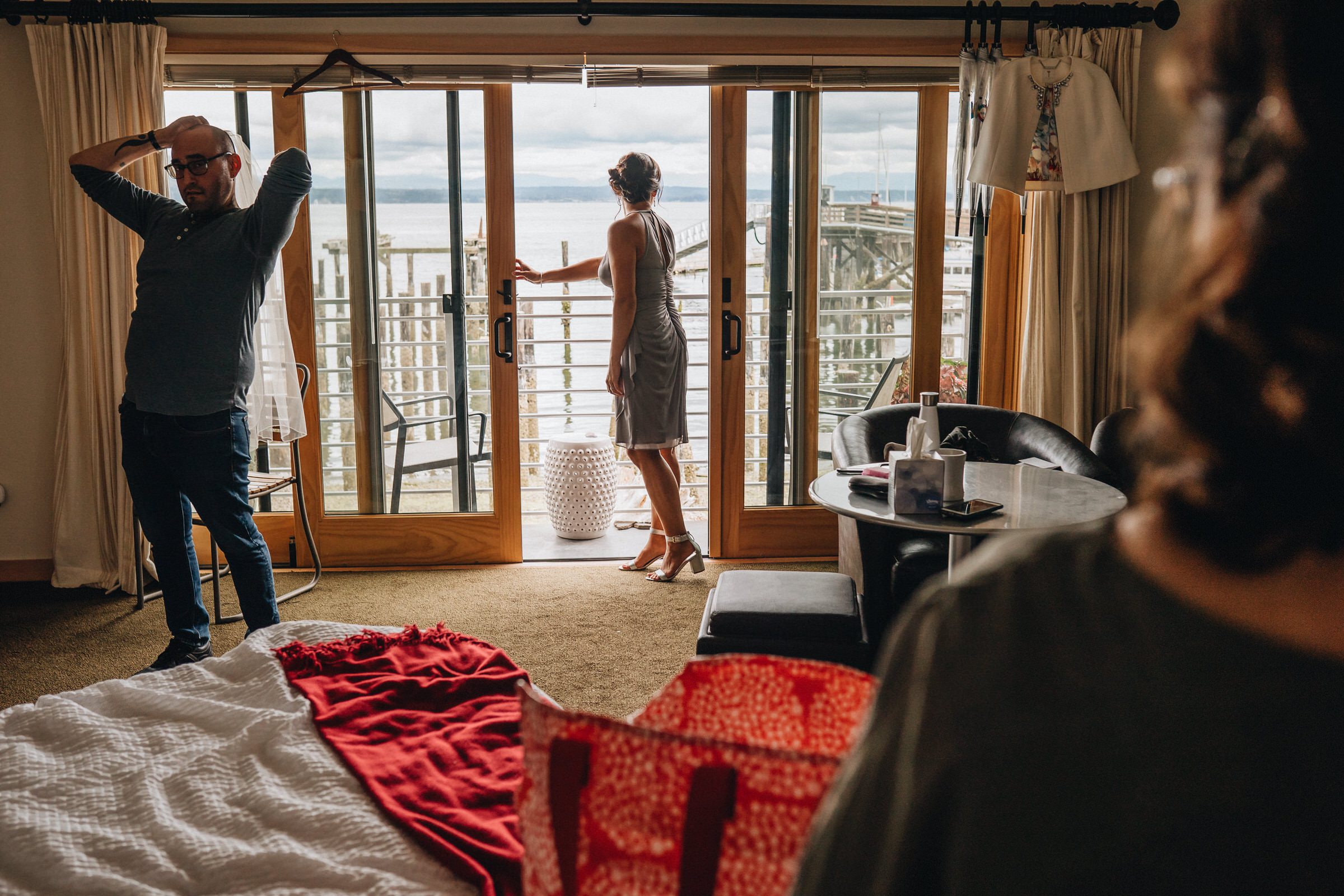 Boatyard Inn Whidbey Island wedding: Funny moment of David, the Hair Guy, putting on Sara's veil as Sylvia checks on the weather outside.