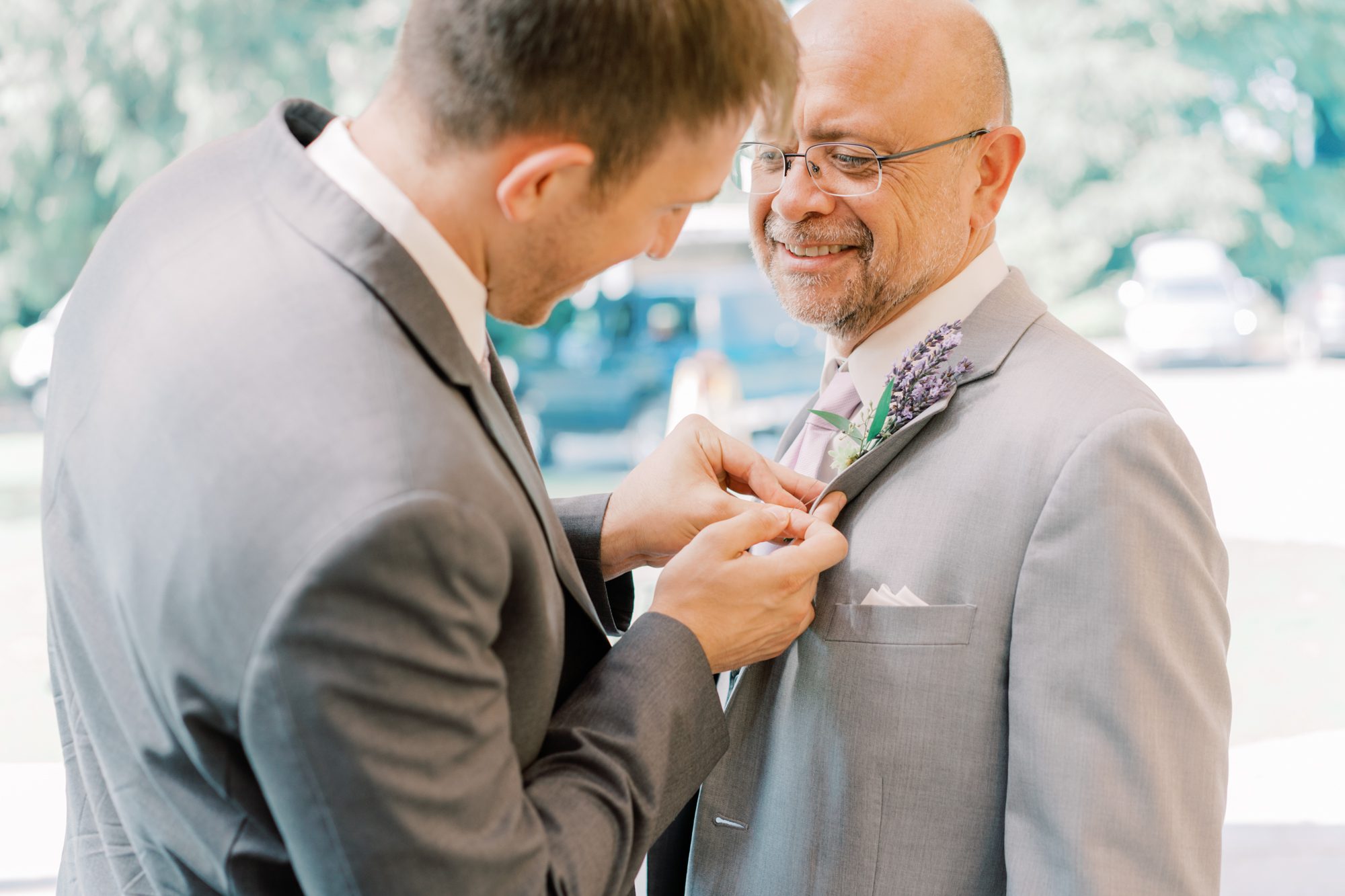 Groom puts boutonniere on dad Groom puts boutonniere on dad