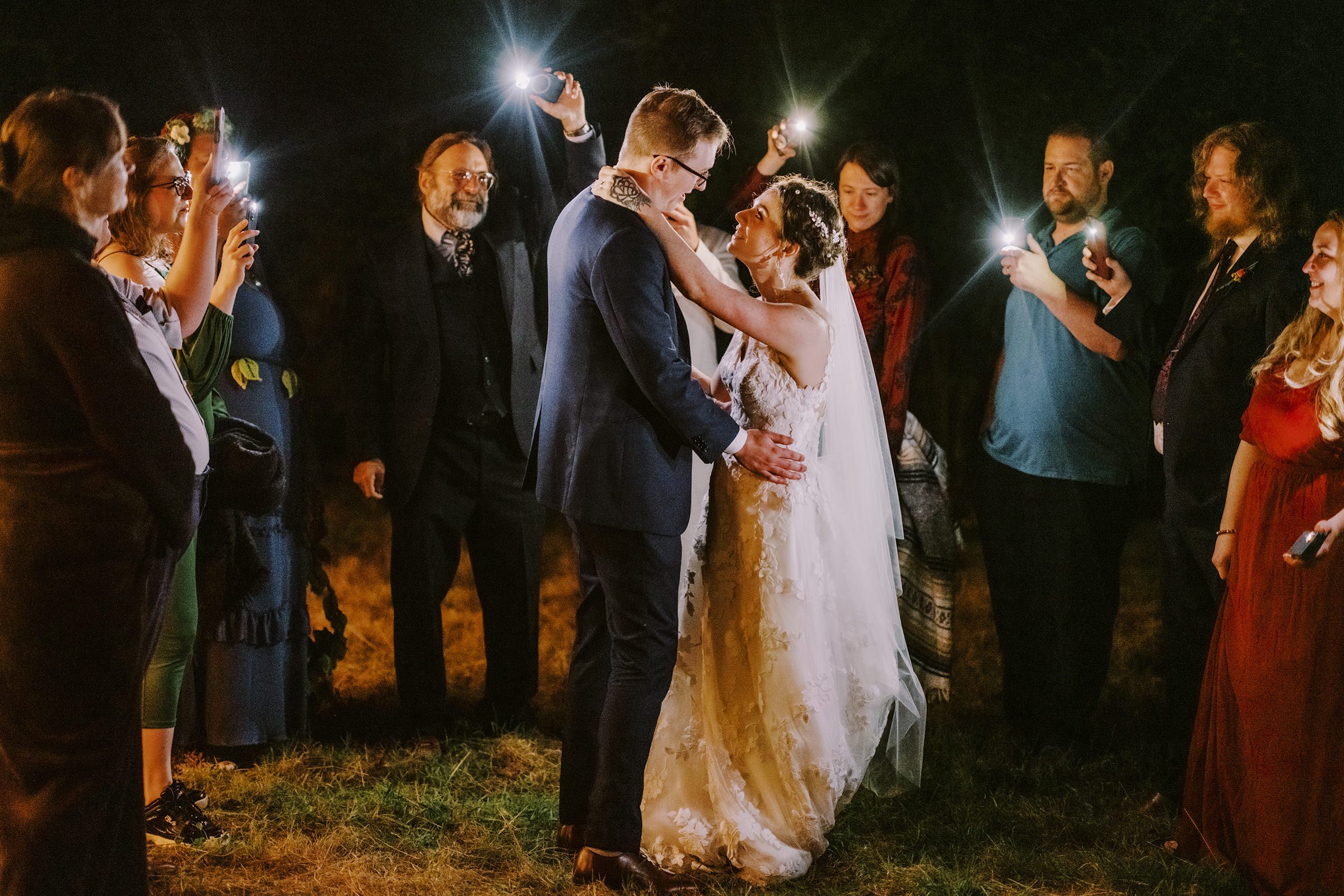 Annika and Sean's first dance lit by their friends and family's phones.